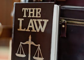 Close-up of a law book titled 'The Law' beside a leather briefcase.